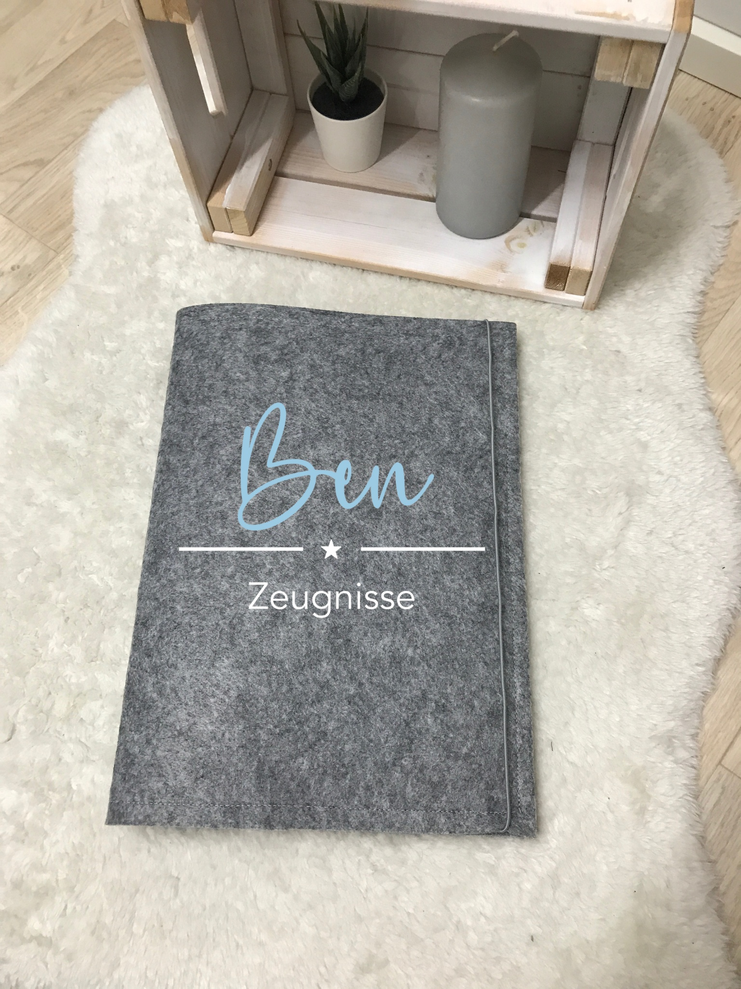 Zeugnismappe Filz DIN A4 auf Teppich, grau mit personalisiertem Namen, stilvolle Dokumentenaufbewahrung.