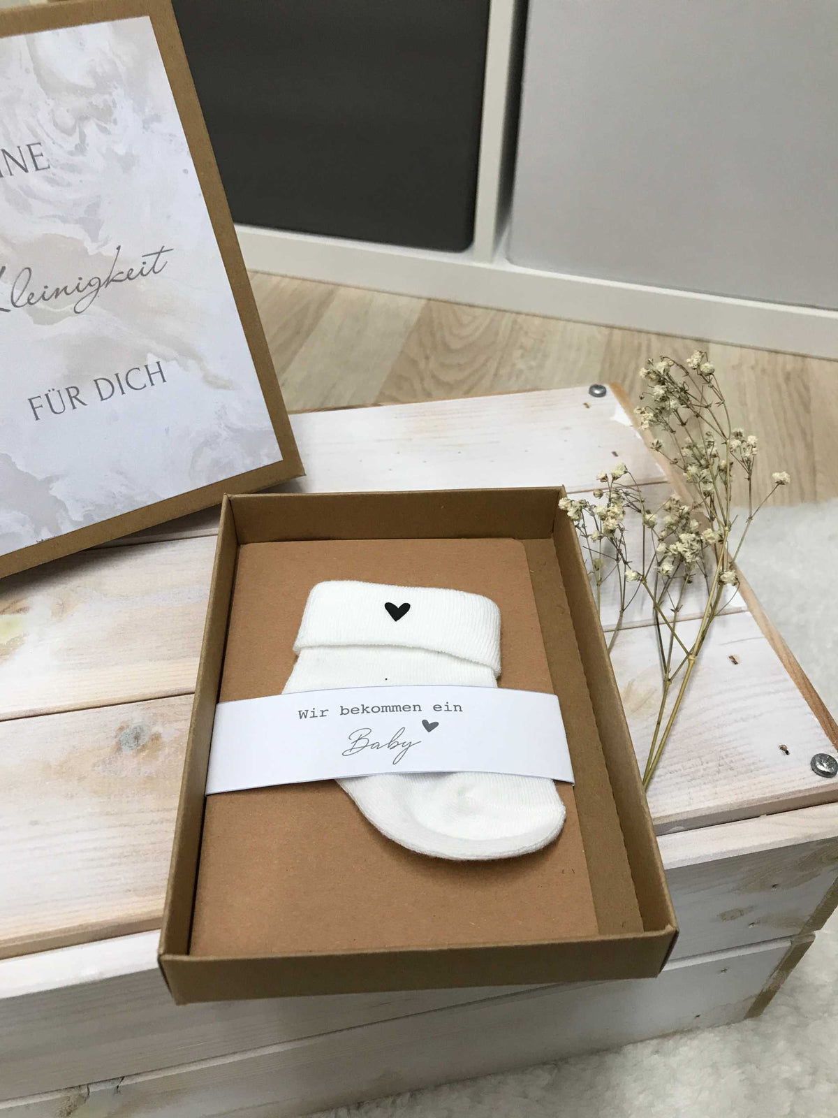 Kreative Schwangerschaftsankündigung mit Geschenkbox und niedlichen Baby-Söckchen zur besonderen Verkündung.