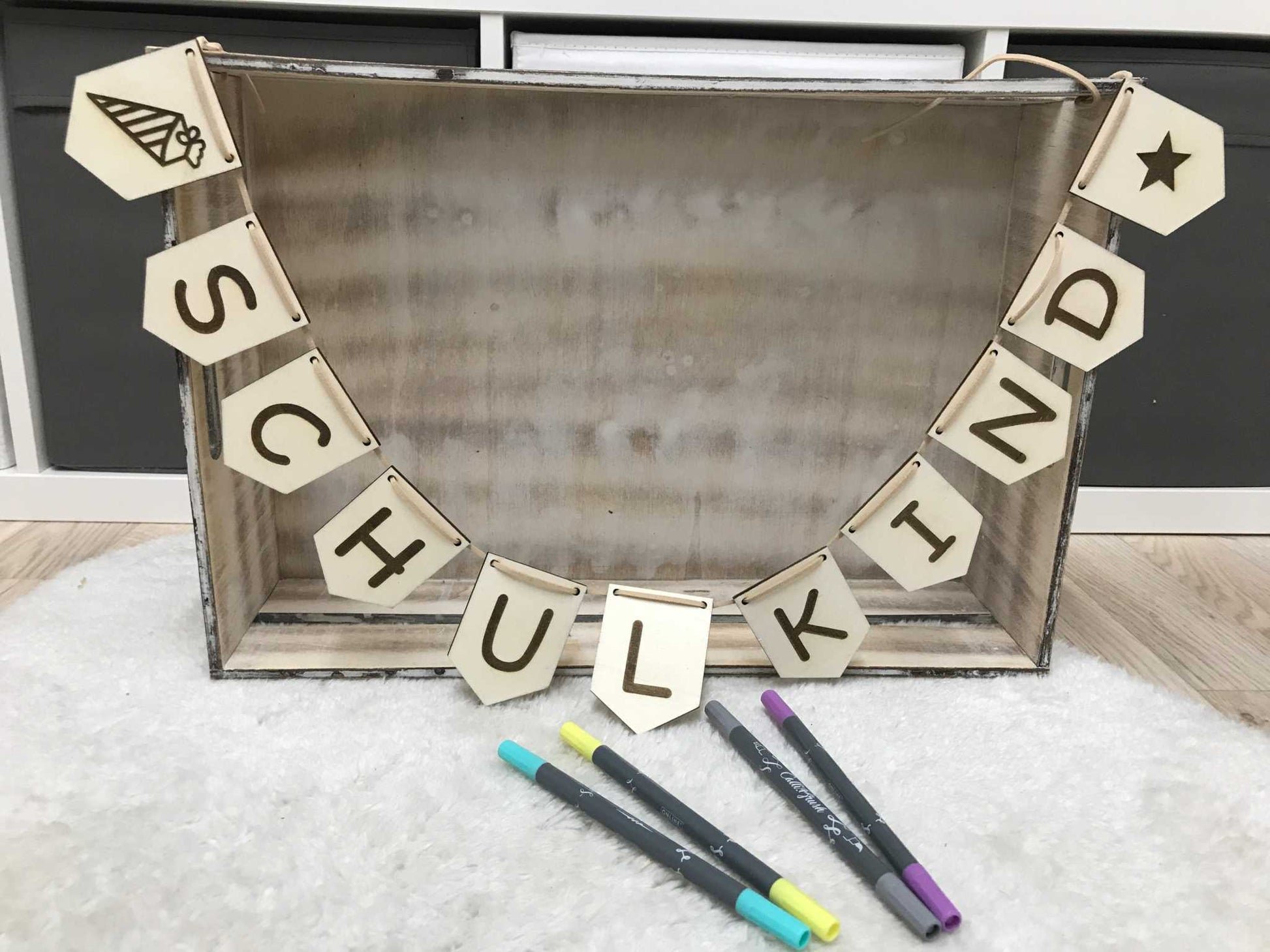 Wimpelkette zur Einschulungsdeko aus Holz, graviert mit „Schulkind“, aufgefädelt auf Lederband, symbolediert mit Schultüte und Stern.