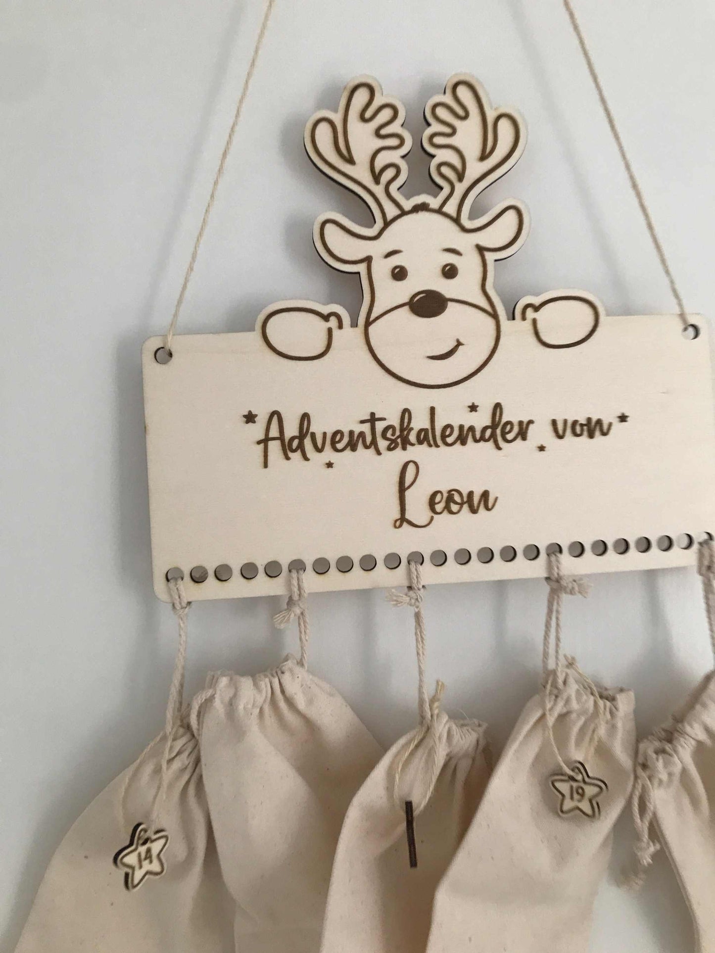 Personalisierbarer Holz-Adventskalender mit Rentiermotiv und 24 beschriftbaren Beuteln.