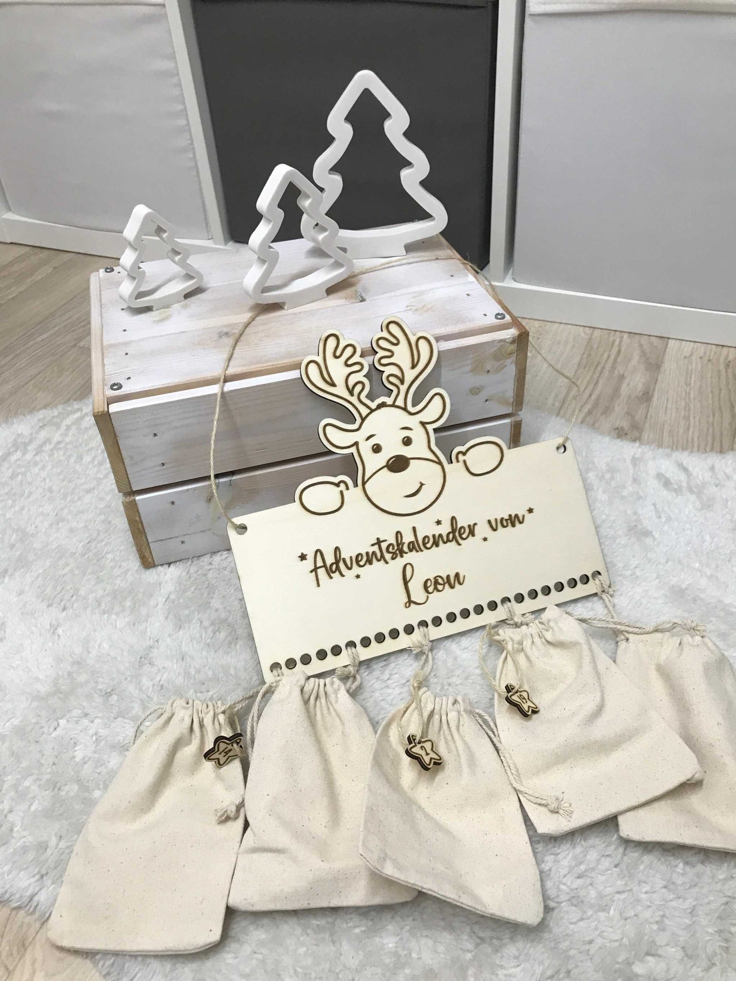 Personalisierbarer Holz-Adventskalender mit Säckchen, Holzschild und Weihnachtshintergrund.