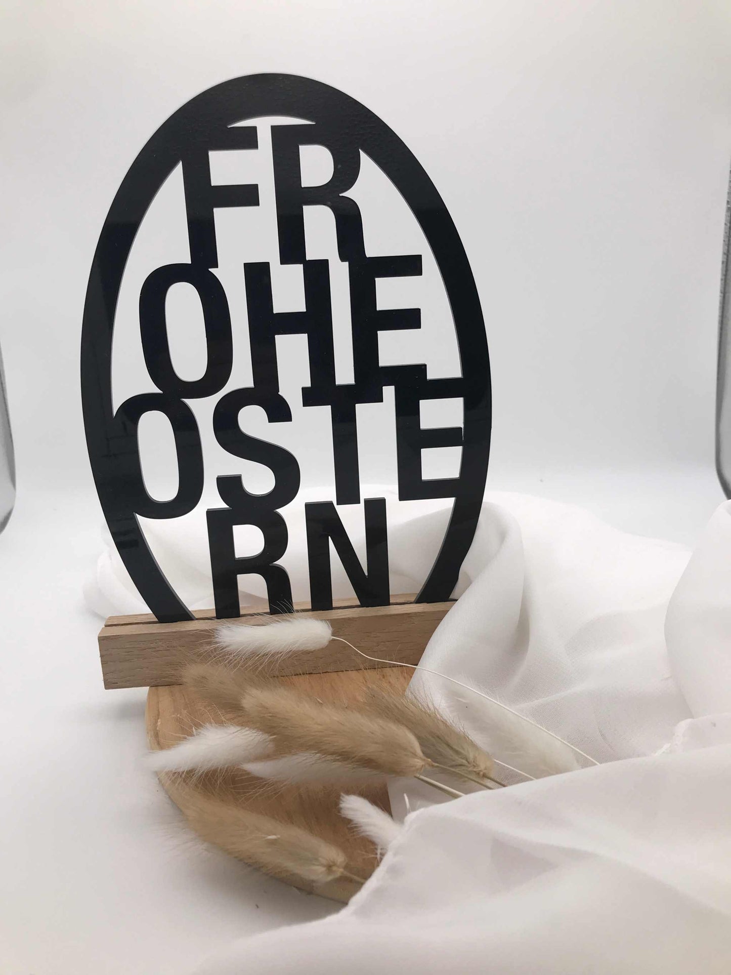 Eleganter "Frohe Ostern" Schriftzug aus Acryl und Holzklötzchen als Osterdekoration auf weißem Hintergrund.