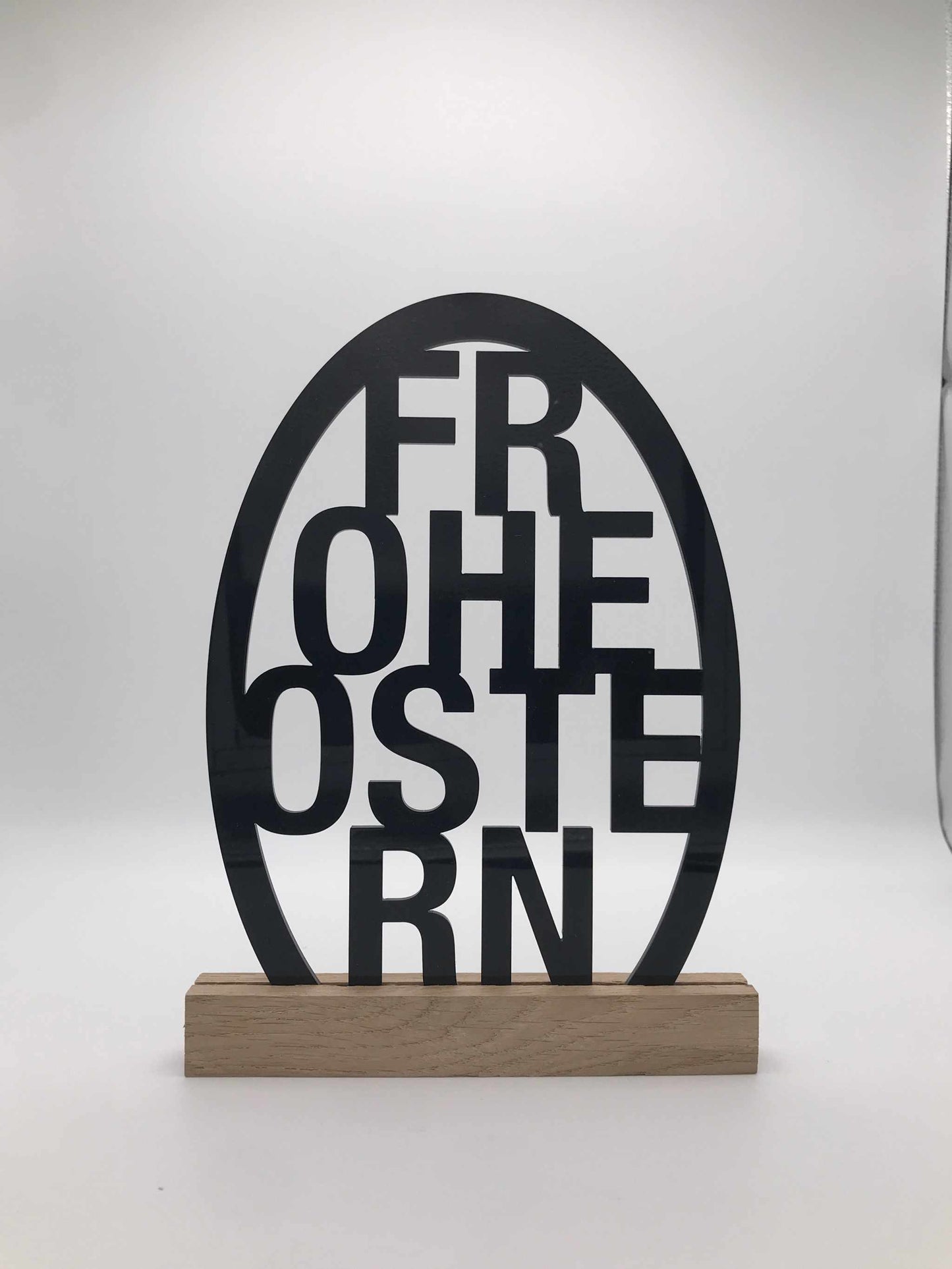 Osterdekoration aus Acryl mit "Frohe Ostern" Schriftzug und Holzklötzchen.