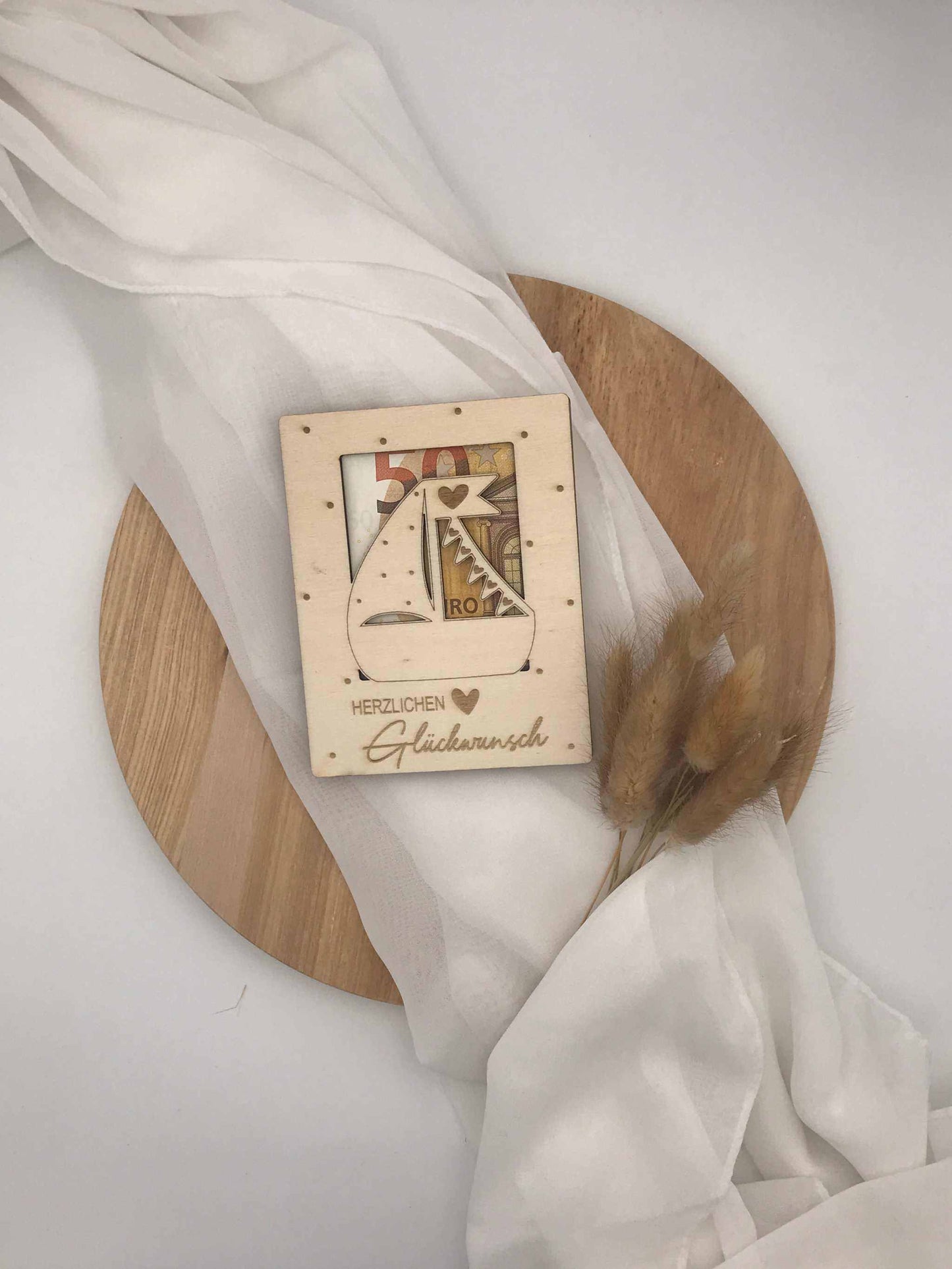 Geldgeschenk aus Sperrholz für Taufe, Kommunion, Firmung oder Konfirmation auf Holzplatte mit Dekorationen.