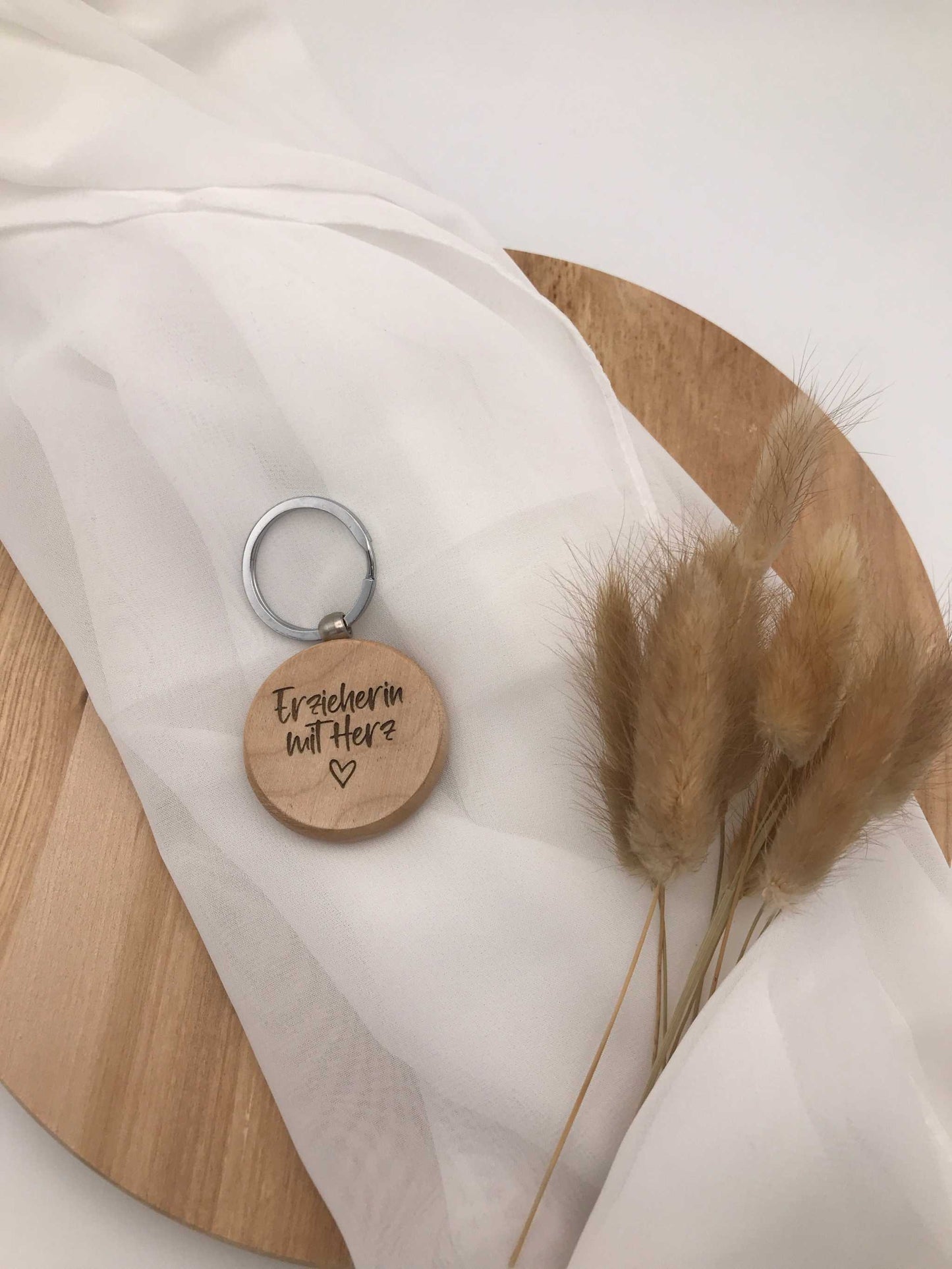 Personalisierter Schlüsselanhänger für Erzieherinnen aus Holz mit Gravur und Herzsymbol auf hellem Untergrund.