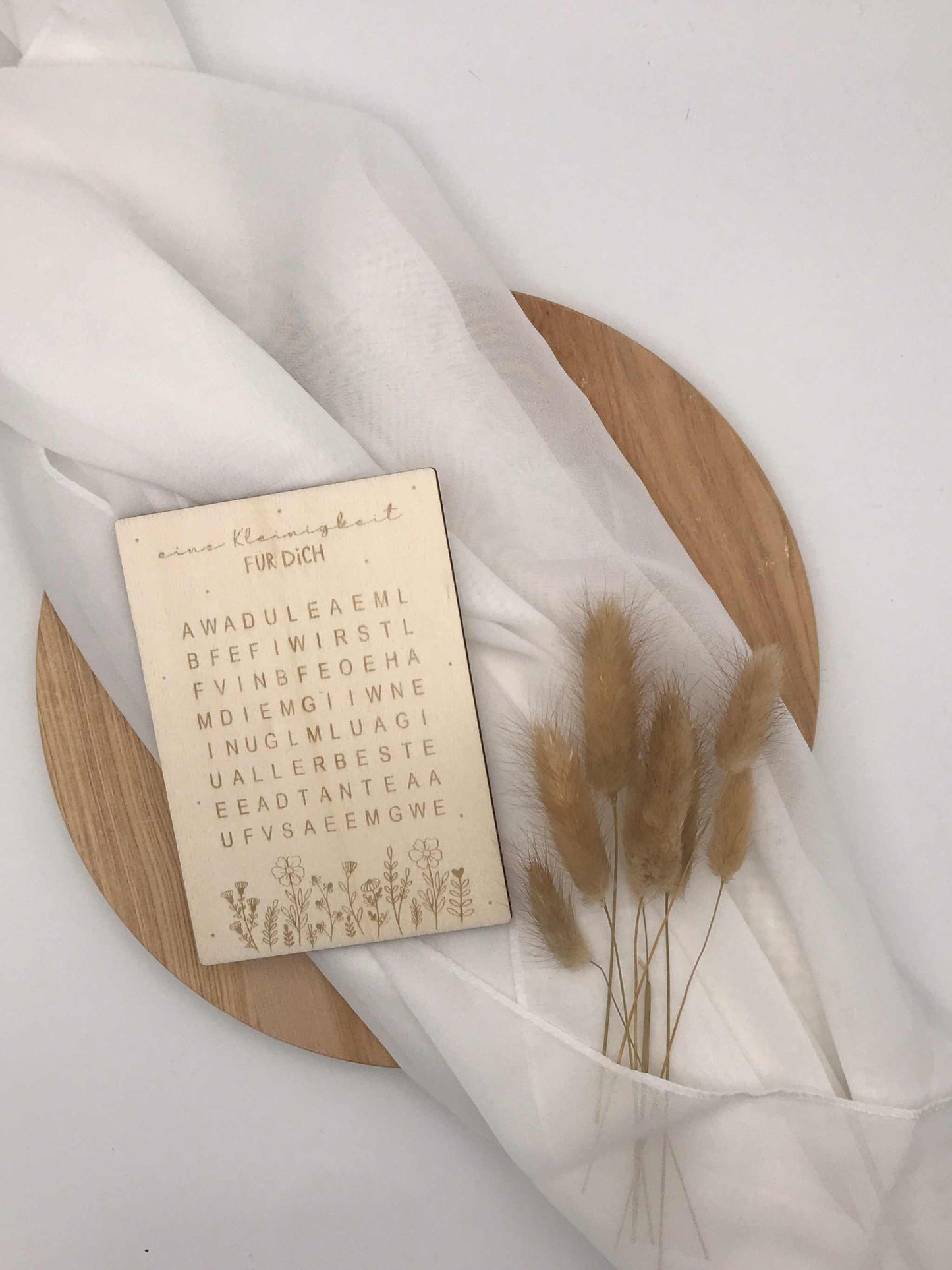 Holzkarte im Worträtsel-Design zur kreativen Schwangerschaftsankündigung, dekorativ präsentiert.