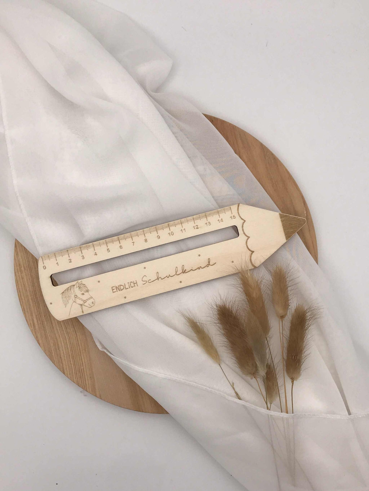 Personalisierte Lesehilfe aus Holz in Form eines Leselineals für die Einschulung, graviert mit Namen und Motiven, auf einem weißen Tuch präsentiert.