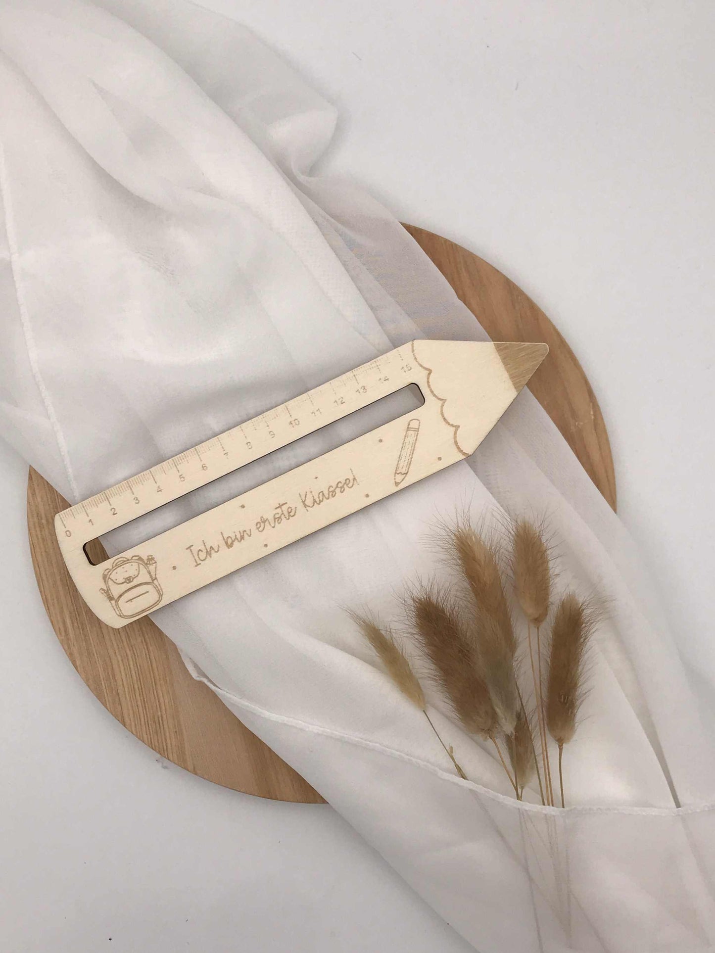 Personalisierte Lesehilfe aus Holz mit Gravur "Ich bin erste Klasse" auf einem weißen Tuch und Holzuntergrund, ideal als Einschulungsgeschenk.