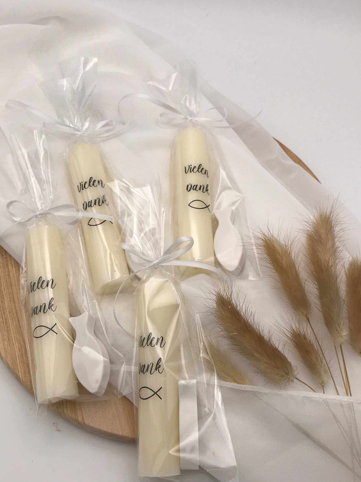 Gastgeschenke zur Taufe mit personalisierten Kerzen und Fischsymbolen, liebevoll verpackt in Zellophan.