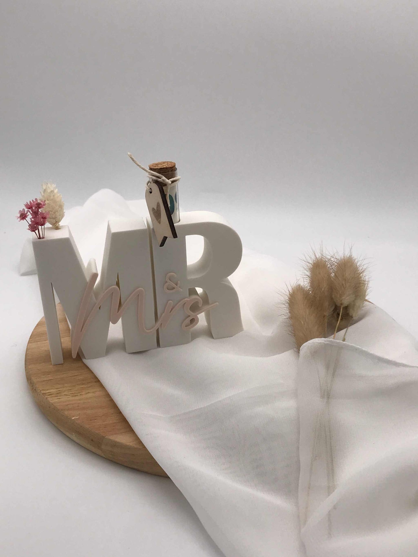 Geldgeschenk zur Hochzeit mit 3D "Mr & Mrs" Schriftzug und Reagenzglas auf Holzplatte.