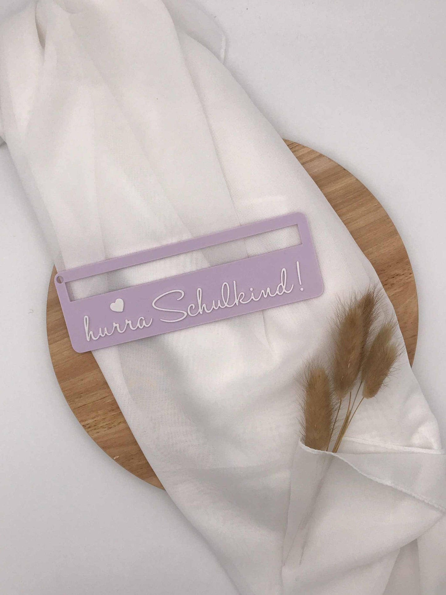 Lila 3D-gedruckte Lesehilfe mit Aufschrift "hurra Schulkind" für Schulanfänger auf weißem Stoff und Holzplatte