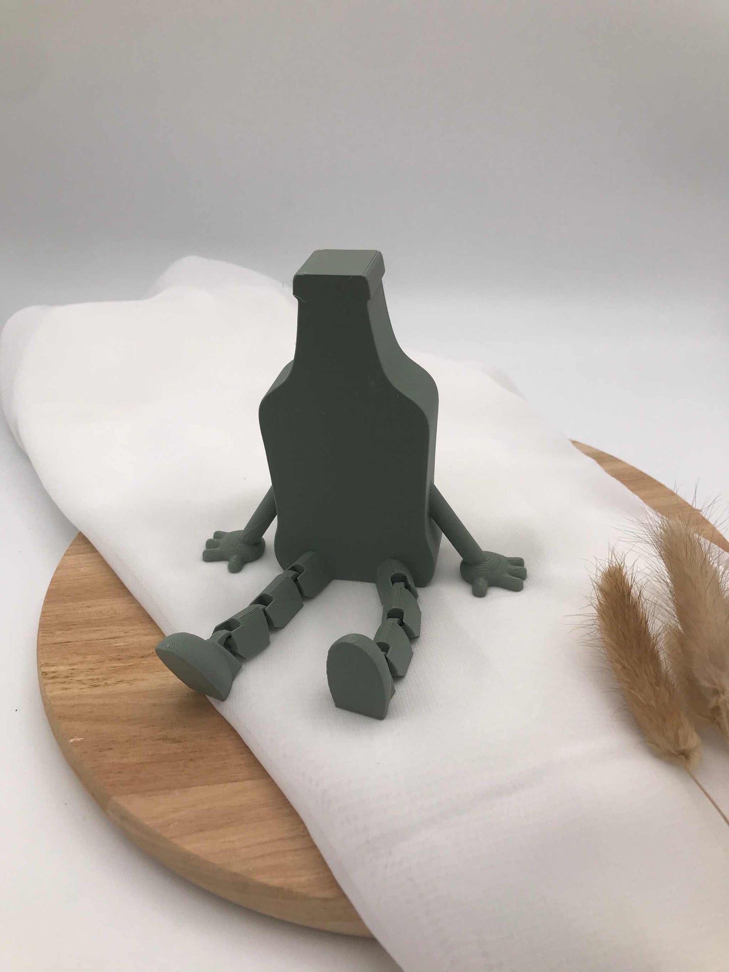 3D-gedruckte Bierflasche mit Wackelbeinen als humorvolle Dekoration auf Holztablett