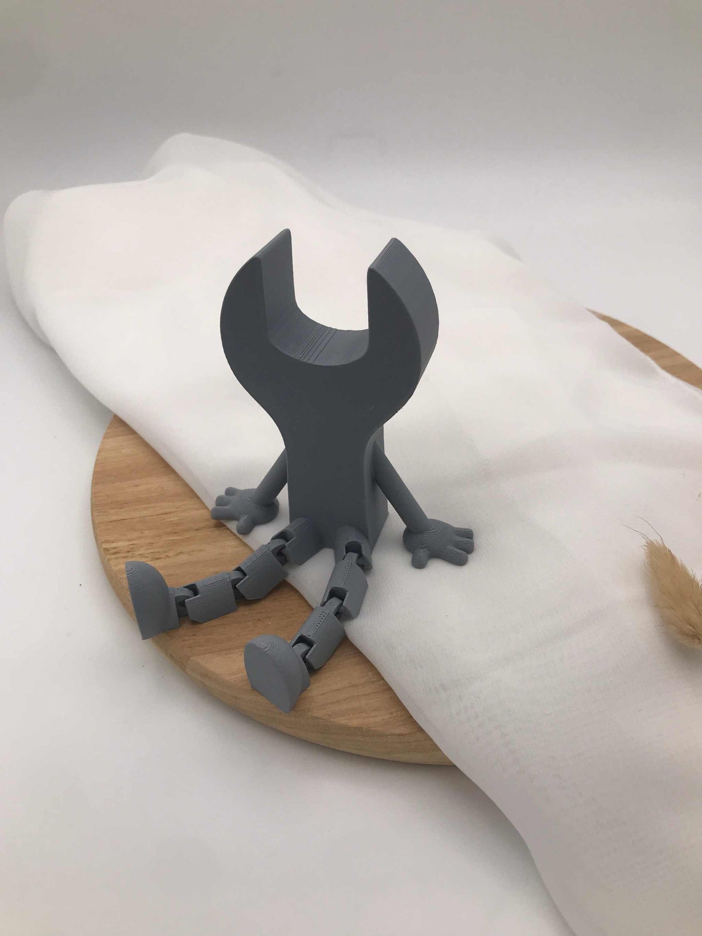 3D-gedruckte graue Schraubenschlüssel-Dekoration mit beweglichen Beinen aus PLA auf Holzplatte
