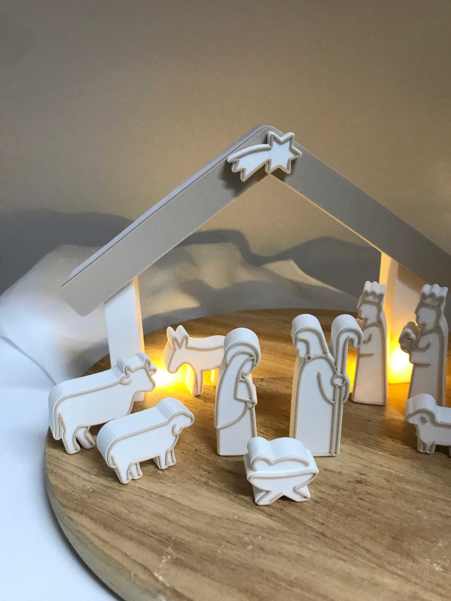 minimalistische weiße Weihnachtskrippe aus 3D-Druck mit Stall und Figuren auf Holzplatte, moderne Adventsdekoration