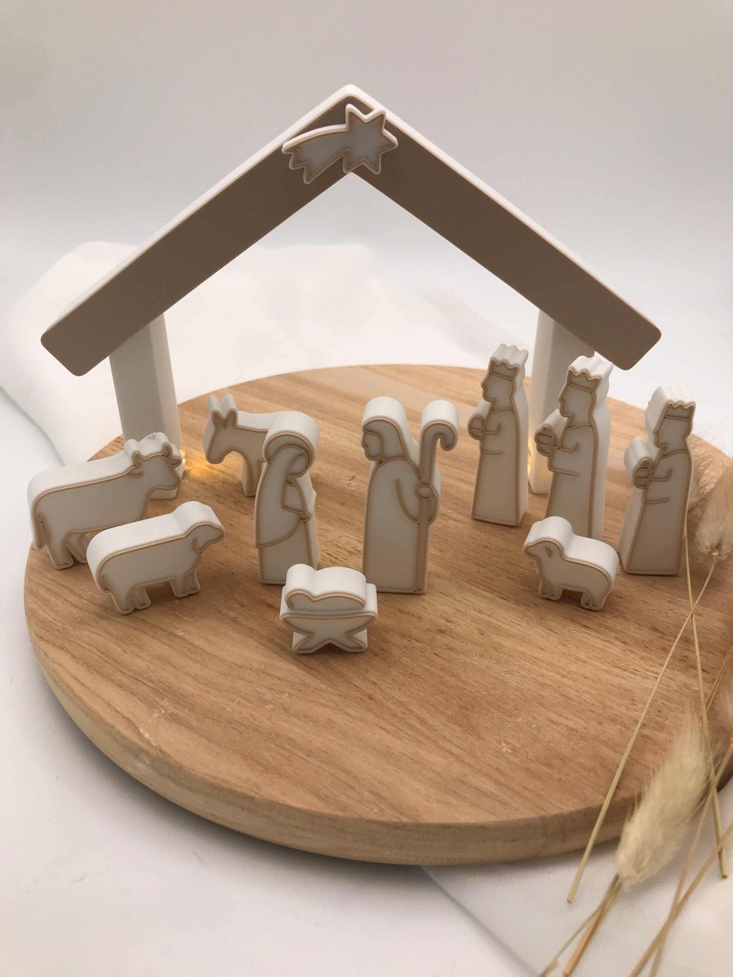 Weihnachten: Minimalistische 3D-gedruckte Weihnachtskrippe aus PLA mit Maria, Josef, Jesuskind, Heiligen Drei Königen, Hirte, Tieren und Stall auf rundem Holztablett.