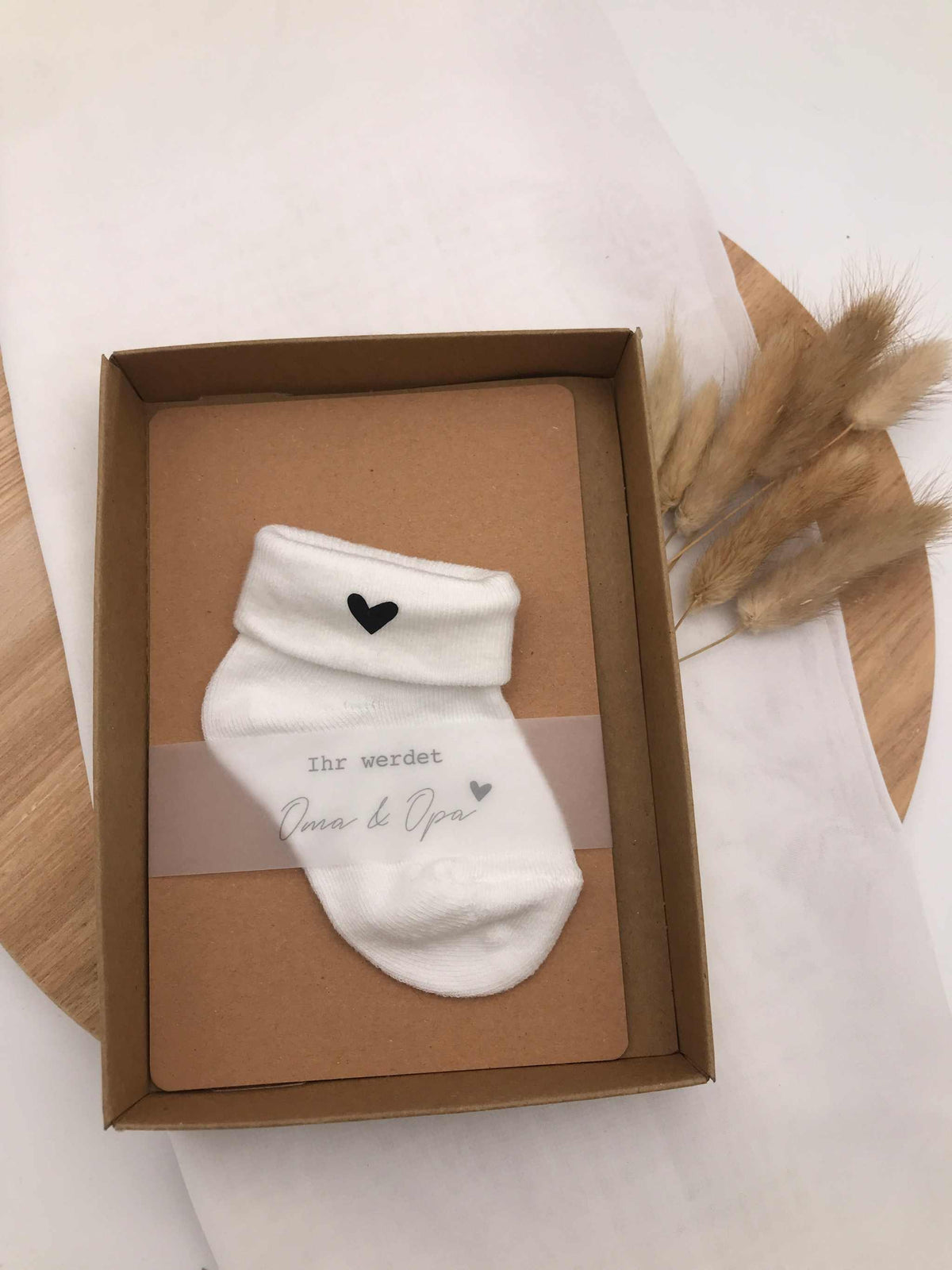 Geschenkbox zur kreativen Schwangerschaftsankündigung mit niedlichen Baby-Söckchen und Herzdetail