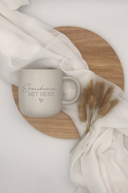 Kaffeetasse "Erzieherin mit Herz" aus Keramik auf Holztablett mit weißem Stoff und Trockenblumen.