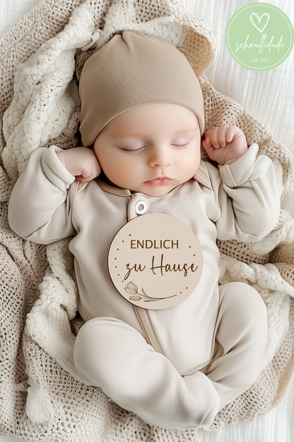 Baby schläft mit Holz-Meilensteinscheibe "Endlich zu Hause", beige Kleidung, stilvolle Fotografie.