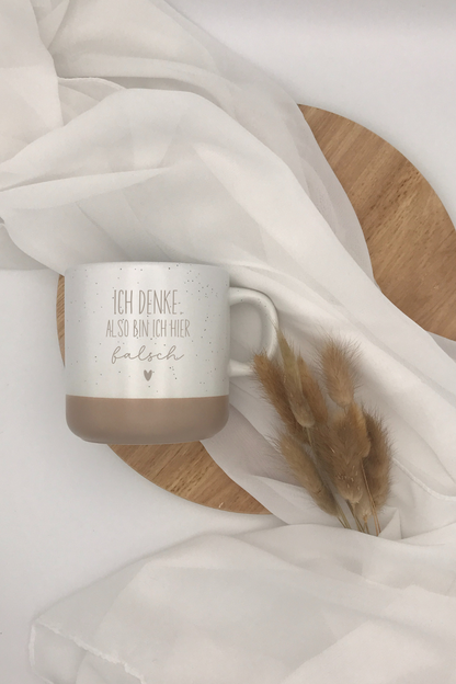 Keramiktasse mit Spruch "Ich denke. Also bin ich hier falsch" in Grau und Beige Design.