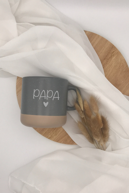 Elegante Keramiktasse mit "Papa"-Gravur in Grau und Beige auf Holzunterlage.