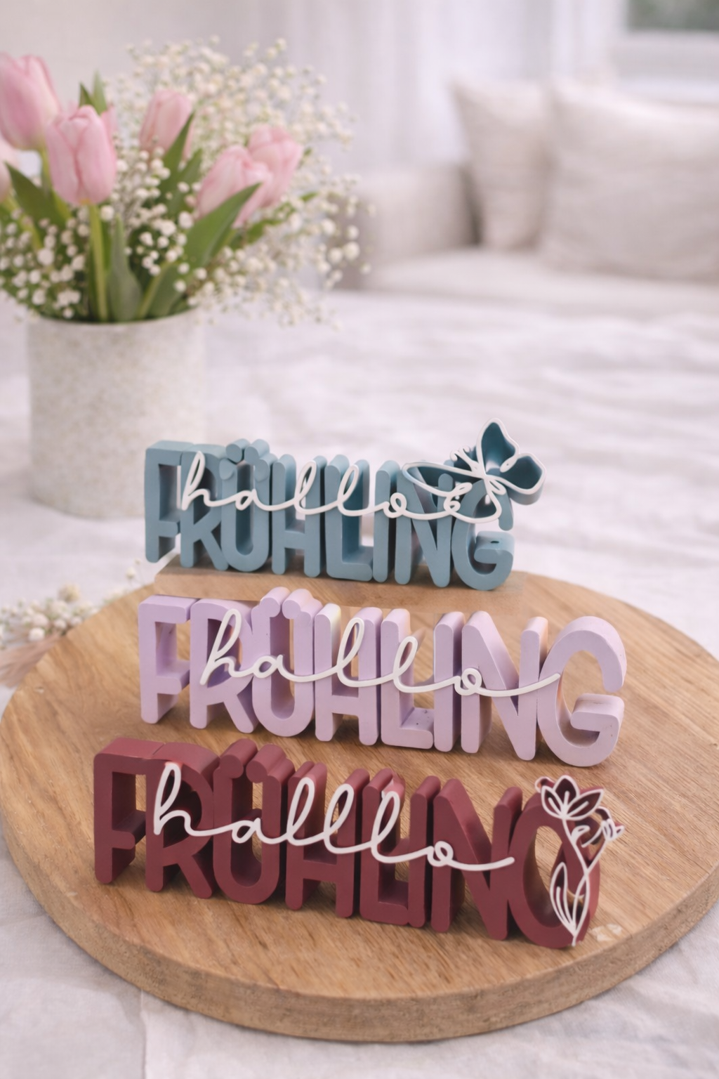 Frühlingsdeko 3D Schriftzug aus PLA in Pastellfarben auf Holztisch mit Tulpen im Hintergrundgefertigte 3D-Druck Deko in frischen Frühlingsfarben