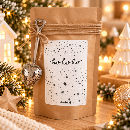 Kaffee in einer naturbraunen Papiertüte mit Jutekordel, herzförmigem Anhänger und weißem „ho ho ho“-Weihnachtsetikett