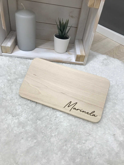 Frühstücksbrettchen mit eingraviertem Namen auf hellem Teppich.