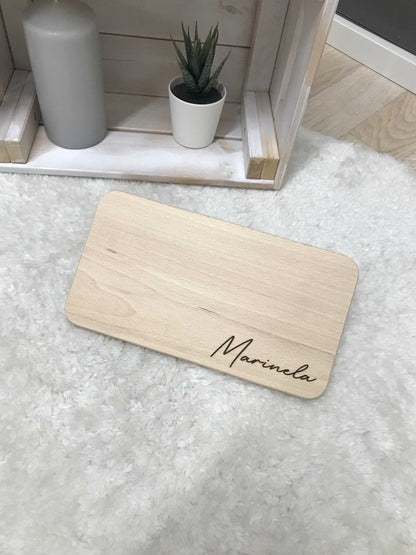 Frühstücksbrettchen mit personalisiertem Namen auf hellem Holz.