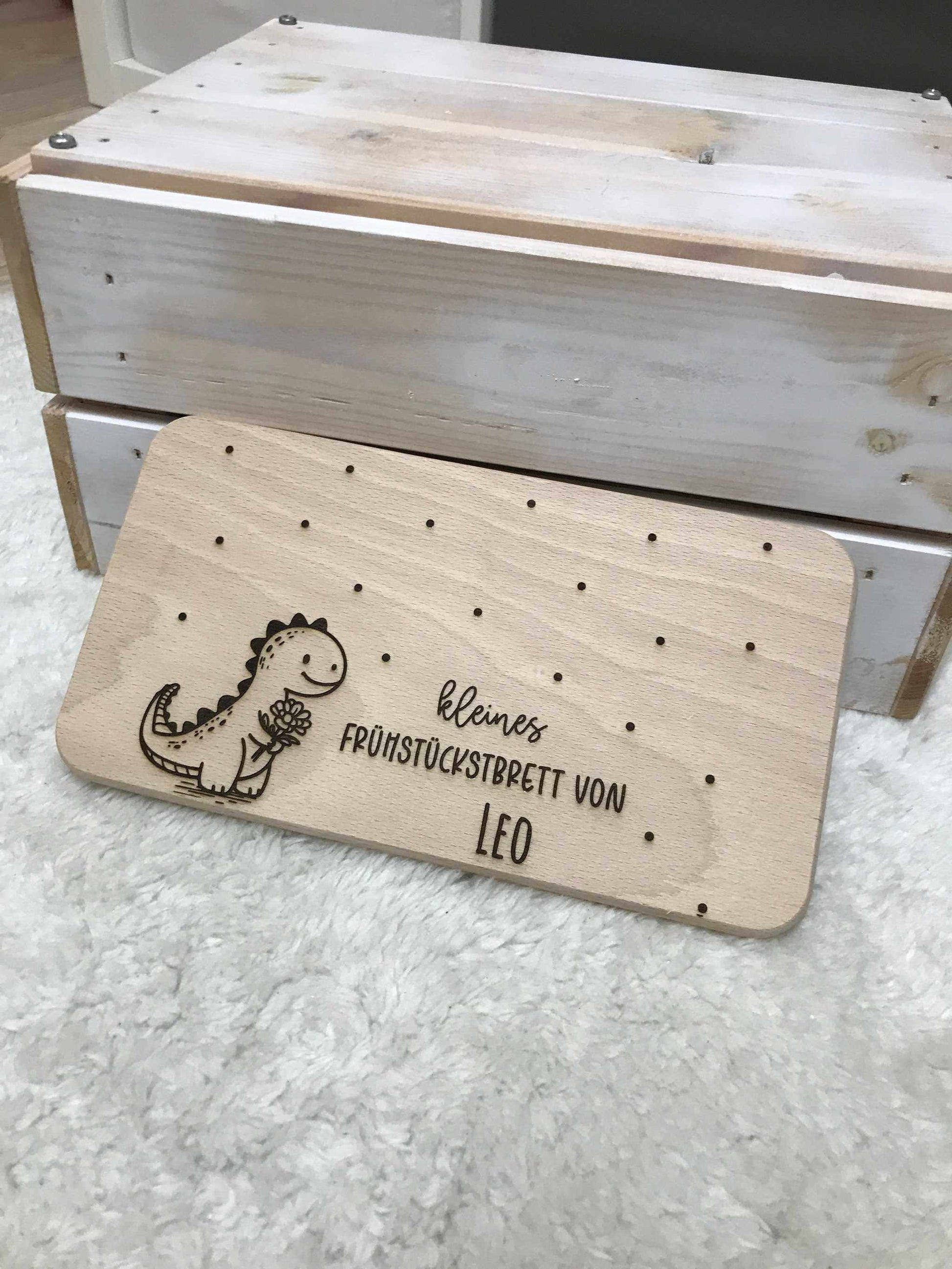 Frühstücksbrettchen mit Dino-Design auf Holztisch.