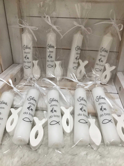 Weiße Kerzen mit Fischmotiv und dem Text "Schön, dass du da bist", verpackt als Gastgeschenke für Taufen, Kommunionen und ähnliche Anlässe.