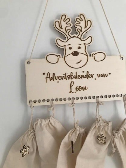 Personalisierbarer Holz-Adventskalender mit Rentiermotiv und 24 beschriftbaren Beuteln.