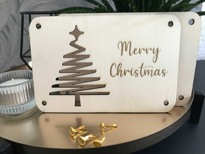 Weihnachtliche Geldkarte mit "Merry Christmas"-Gravur und Baumdesign, festlich verpackt.