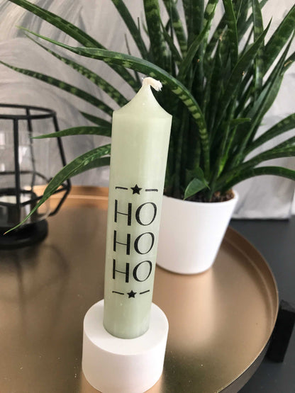 Festliche grüne Stabkerze mit "Ho Ho Ho" Schriftzug, stilvolle Weihnachtsdekoration auf goldenem Tablett.