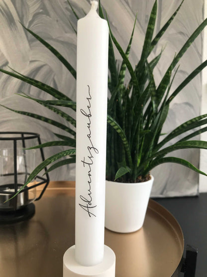 Kerzen mit eleganter Aufschrift neben Dekoration und Pflanze.