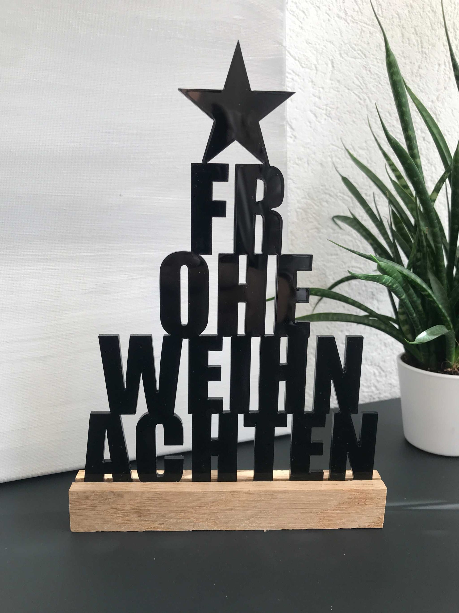 Weihnachtsdekoration "Frohe Weihnachten" Schriftzug aus Acryl und Holz auf Tisch.