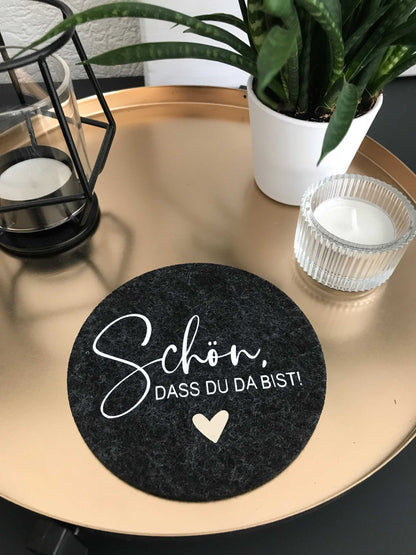 Filzuntersetzer "schön, dass du da bist" auf einem Tisch mit Pflanzen und Kerzen.