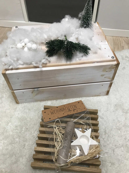 Weihnachtsgeschenk Kerze mit Kerzenständer und Stern-Dekoration in Geschenkbox auf weißem Teppich.