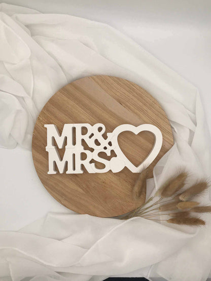 Schriftzug "Mr & Mrs" aus Raysin als elegante Tischdekoration auf Holzteller mit Trockenblumen.
