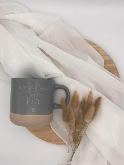 Keramiktasse "coffee love" in Grau und Beige mit Lasergravur auf weißem Hintergrund.