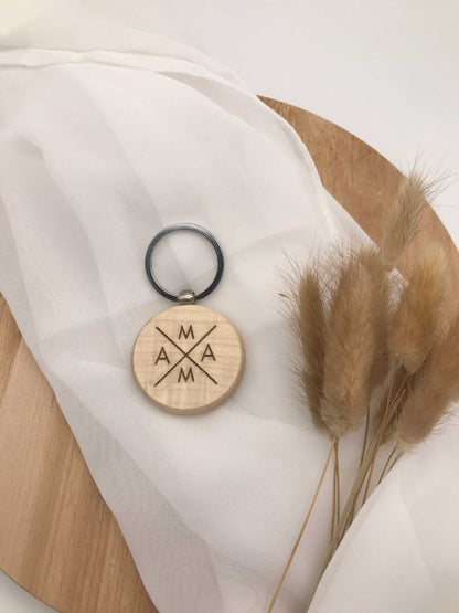 Einzigartiger Holz-Schlüsselanhänger mit Gravur und Pflanzen auf Stoff drapiert.