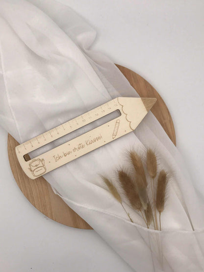 Einschulung personalisierte Lesehilfe aus Holz mit Gravur auf weißem Tuch drapiert.