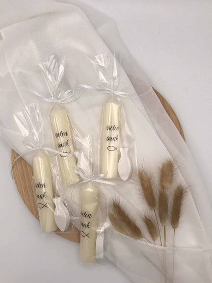 Gastgeschenke zur Taufe oder Kommunion: Weiße Kerzen mit Aufschrift "Vielen Dank" und Fisch-Symbol, dekorativ verpackt auf Holztablett.
