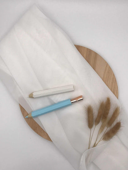 3D-gedruckter Buntstift als kreatives Geldgeschenk zur Einschulung auf Holzplatte drapiert.