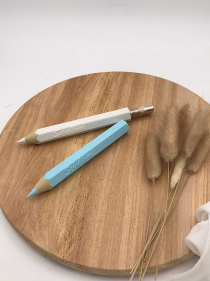 3D-gedruckter Buntstift als Geldgeschenk zur Einschulung, auf Holzuntergrund mit Dekoration.
