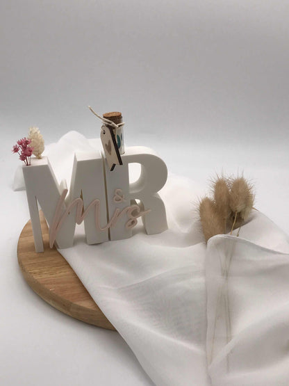 Geldgeschenk zur Hochzeit mit 3D "Mr & Mrs" Schriftzug und Reagenzglas auf Holzplatte.