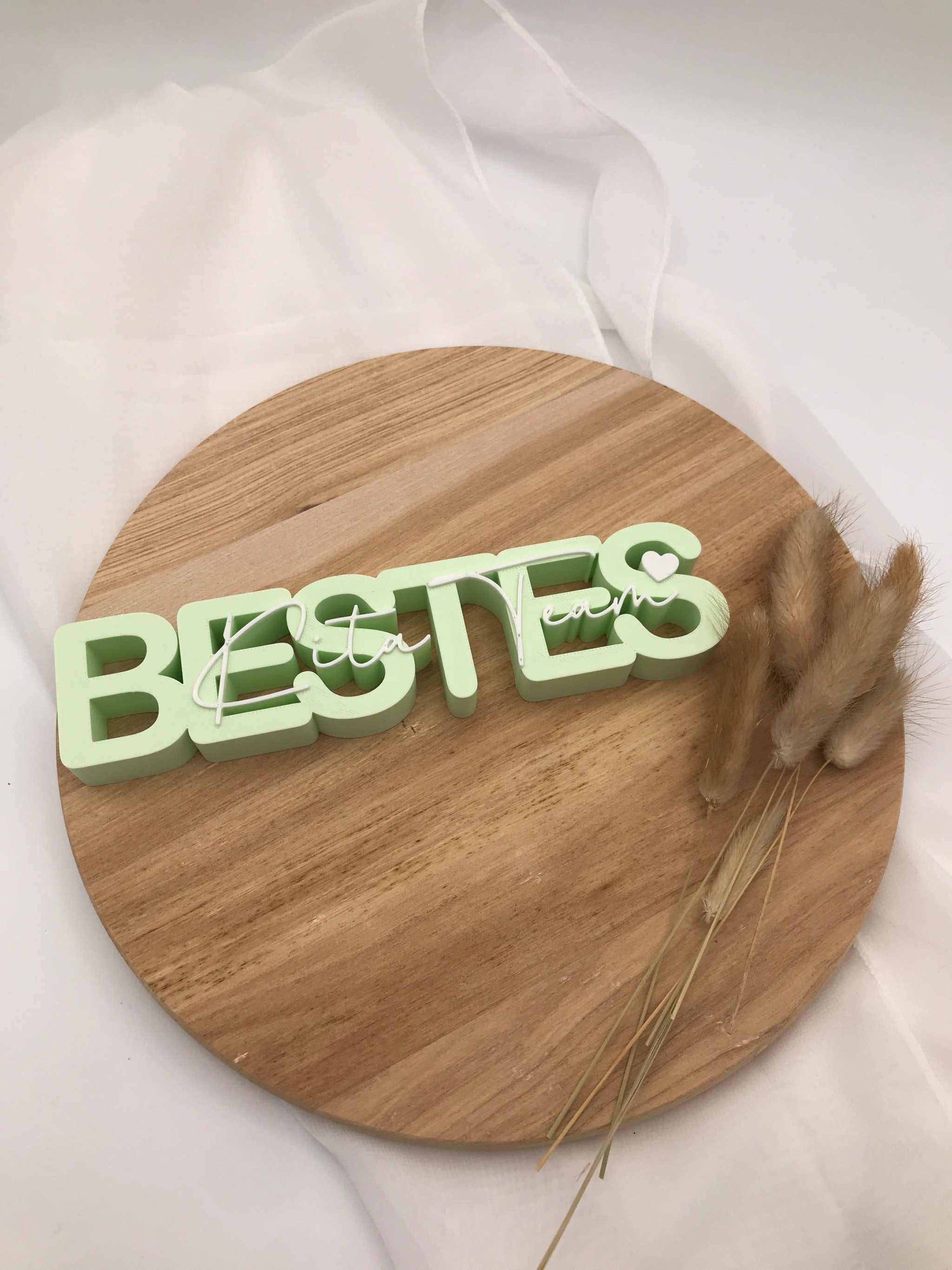 3D-Druck Aufsteller „Bestes Kita-Team“ als Abschiedsgeschenk für Kindergarten Erzieher:innen auf Holzuntergrund.