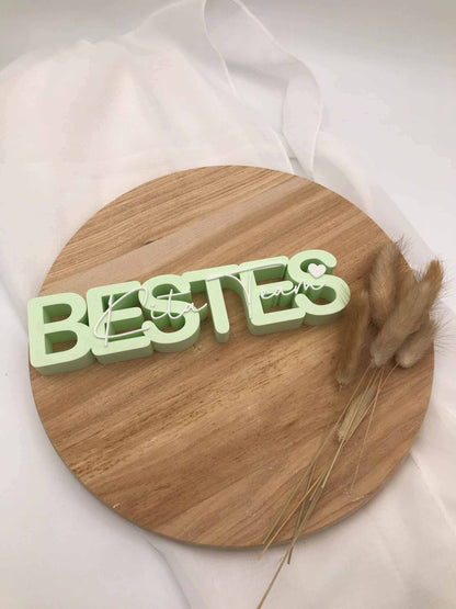 3D-Druck Aufsteller „Bestes Kita-Team“ auf Holzuntergrund mit weißem Stoff und Trockenblumen.