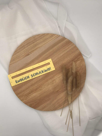 Lesehilfe für Schulanfänger aus 3D-Druck mit der Aufschrift "Endlich Schulkind" auf Holzuntergrund.