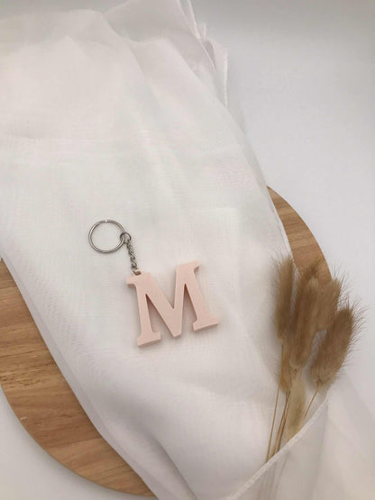 3D-gedruckter Buchstaben-Schlüsselanhänger "M" in Hellrosa auf weißem Hintergrund.
