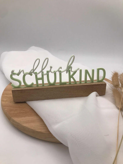 3D-gedruckter Schriftzug „endlich Schulkind“ grün auf Holzsockel als Einschulungsdekoration